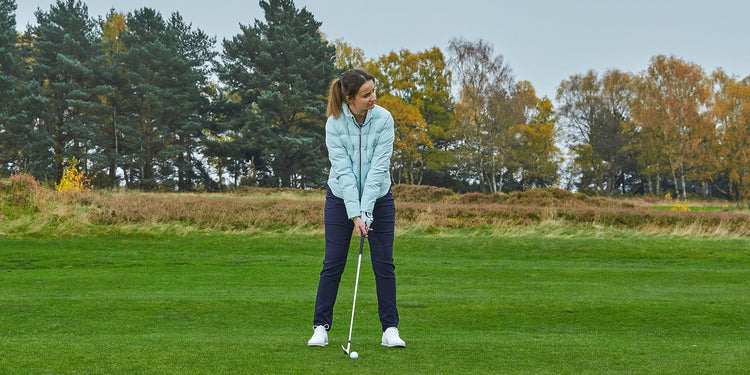 Golfter preparing to take her shot in a FootJoy padded mint blue jacket