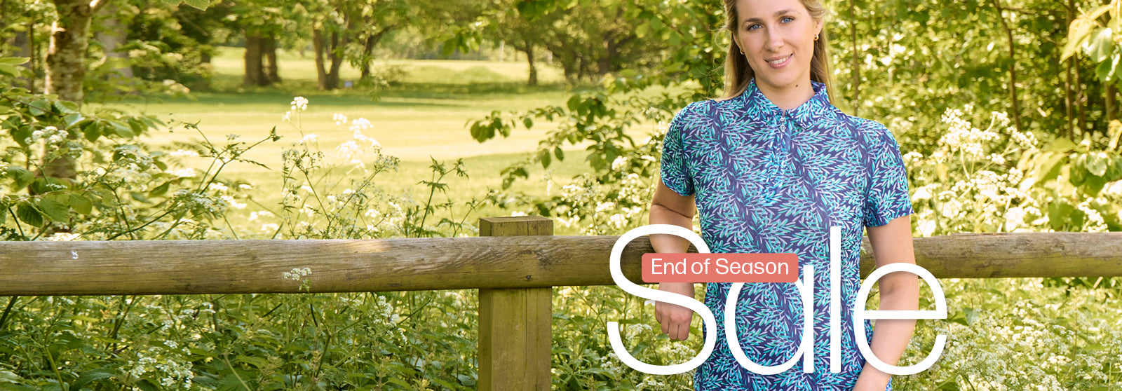 Golfer in Pure Golf mesh polo in a botanical print leaning on a fence at a golf course