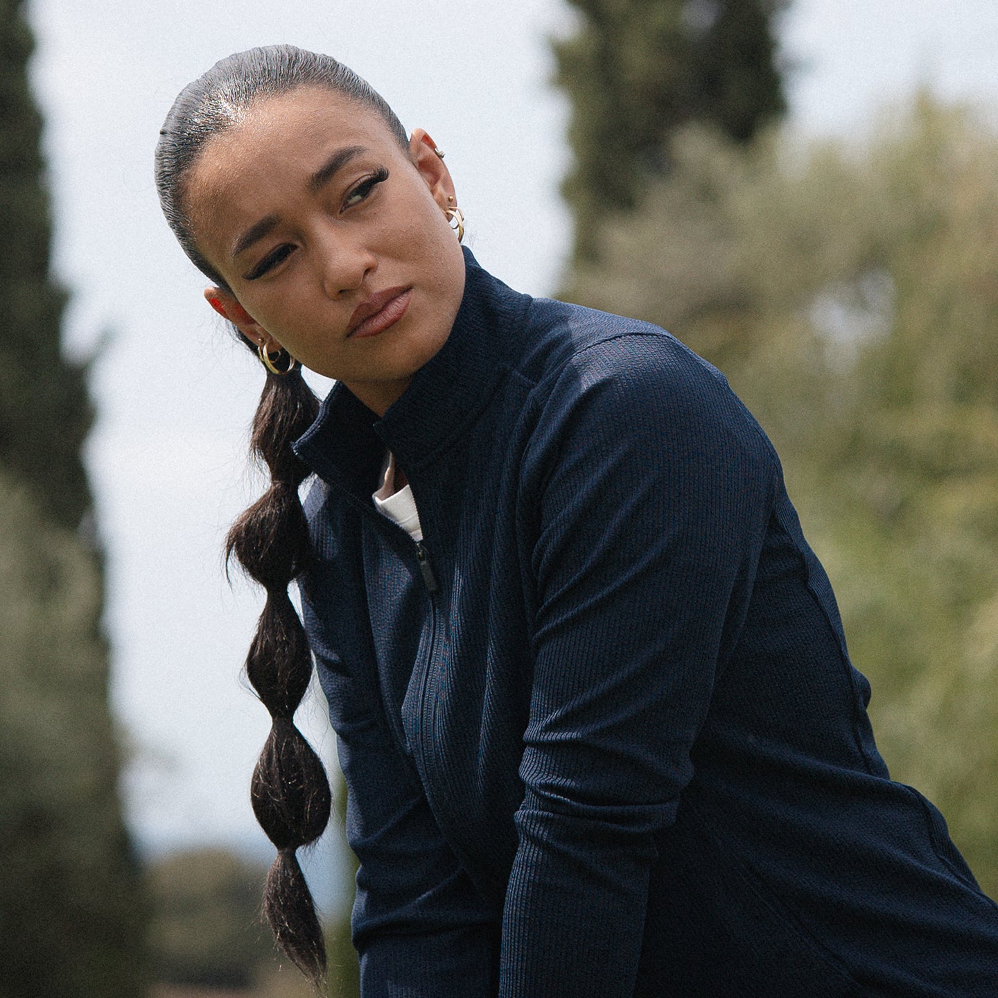 Female golfer lining up her shot in the adidas textured jersey jacket in navy