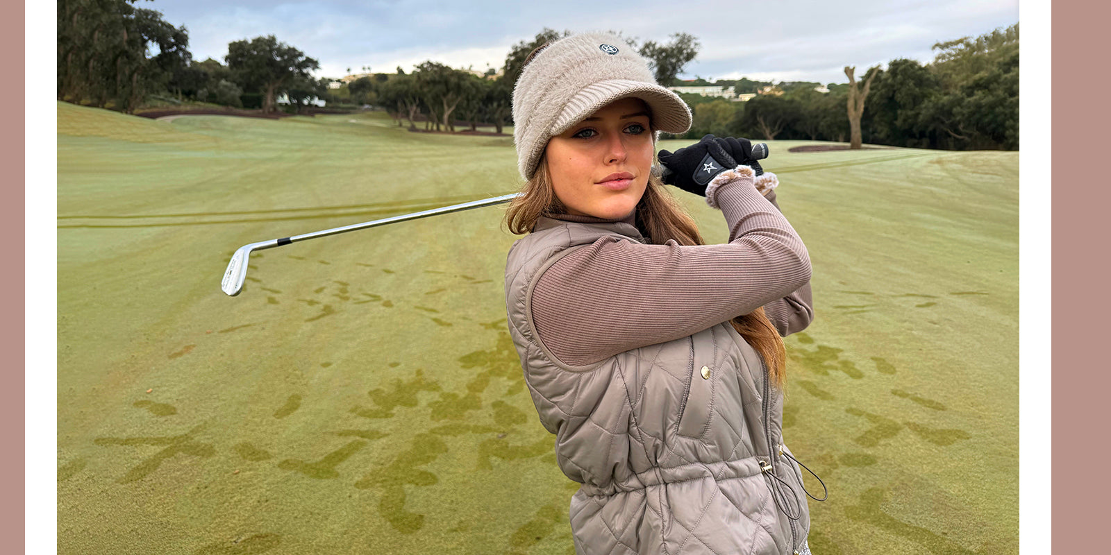Golfer completing her swing wearing a Swing out Sister knit winter visor, gilet and roll neck