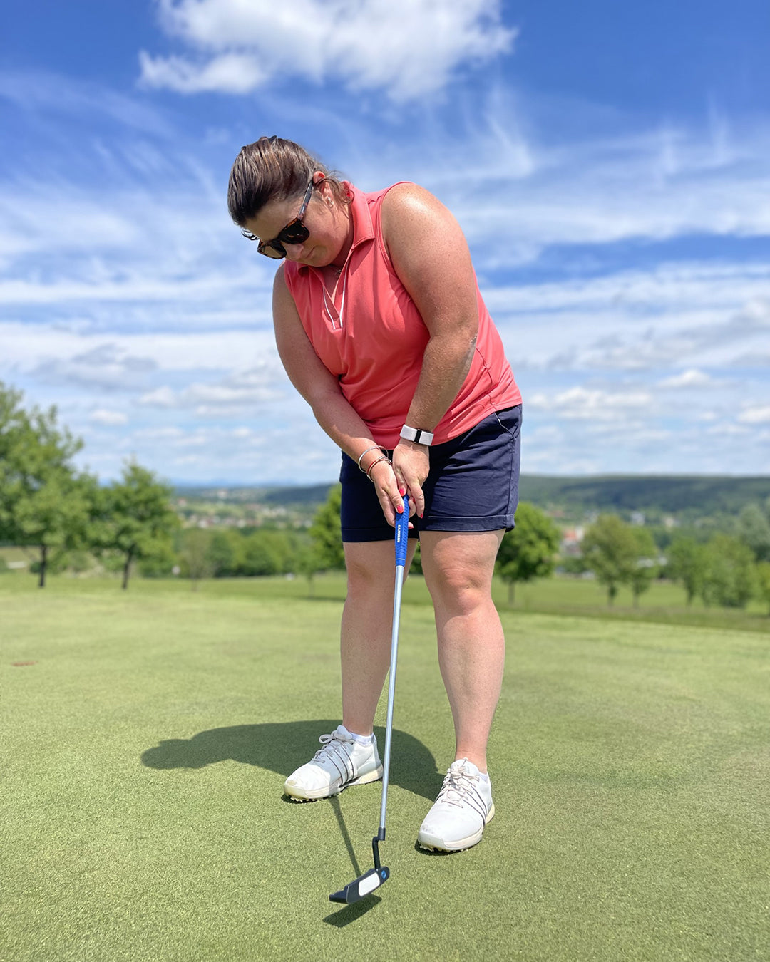 Pro Golfer Sarah Gee wears the Puma GOlf sleeveless v neck polo in peach frost with white piping teamed with navy shorts